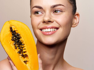 Fresh papaya fruit held by woman with slice in front on white background in bright light