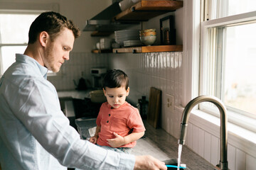 father brushing toddler's son teeth