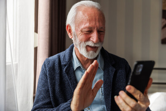 Senior man waving hand on video call
