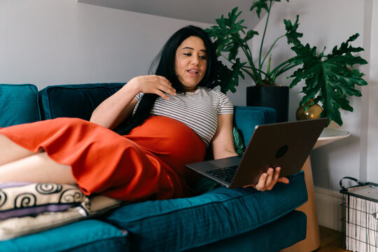 pregnant woman sitting with feet up on sofa  FaceTiming 