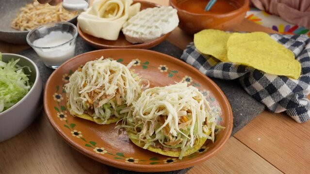 a mexican woman pouring sour cream on mexican tostadas