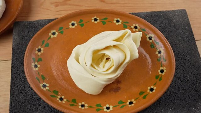 Mexican cheeses displayed on a clay plate (Oaxacan cheese, quesillo, round fresh cheese)