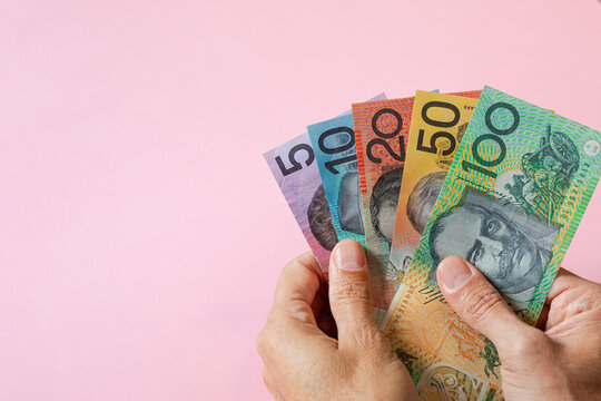 A hand holding Australian money in different dollar values