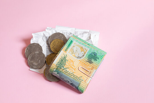 A stack of folded Australian money bills with coin change and receipt