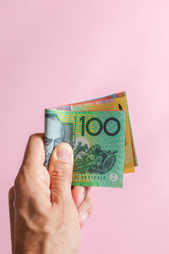 A hand holding several Australian currency dollars bills