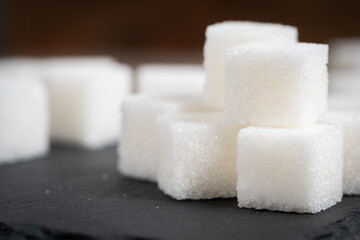 Refined sugar cubes on slate. Food item.