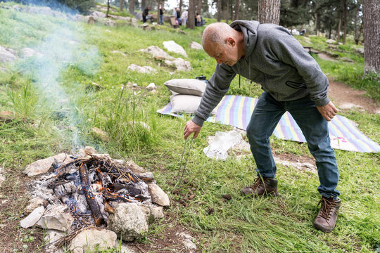 Senior Man Making Campfire in Forest.