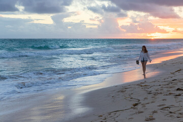 Girl walks the beach in the sunrise