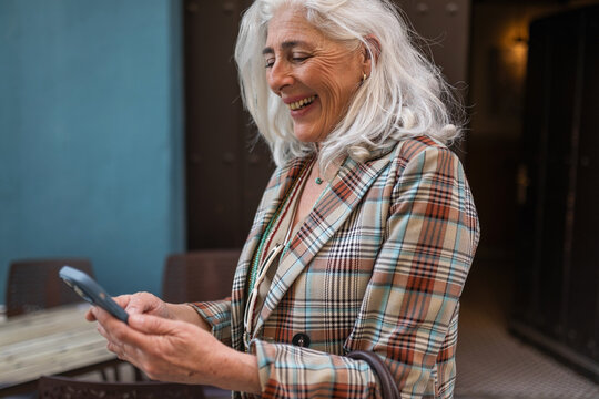 white-haired woman using mobile phone outdoors in the city