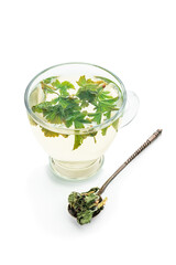 Tea in a glass cup with leaves of black currant isolated on white