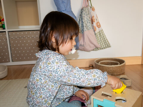 Toddler playing with wooden toy in nursery room