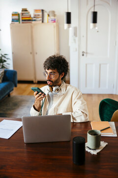 Man sending audio message at home