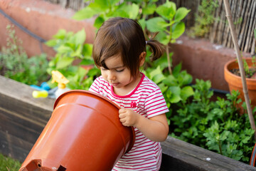 Little girl playing with orange bucket in garden