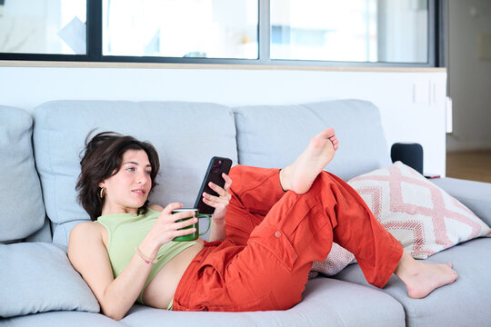 Woman laying on couch surging the net with her smartphone