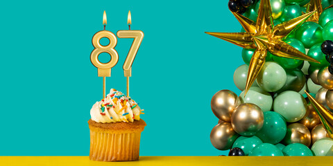 Birthday candle number 87 - Cupcake with decoration on a green background
