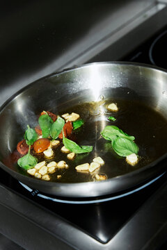 Frying garlic, tomatoes and basil in a frying pan 
