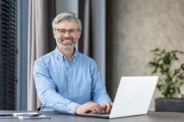 A Professional is Smiling While Working with a Laptop in a Modern Office Setting
