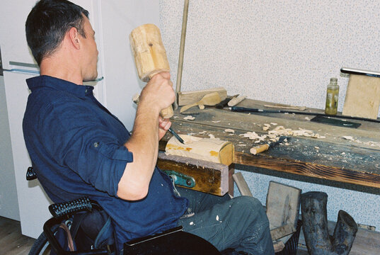 A master woodcarver in a wheelchair at home
