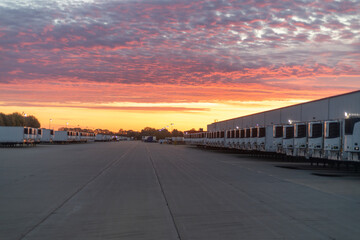 Row of Parked Semi-Trucks Under Beautiful Sunset Sky at Trucking Terminal	
