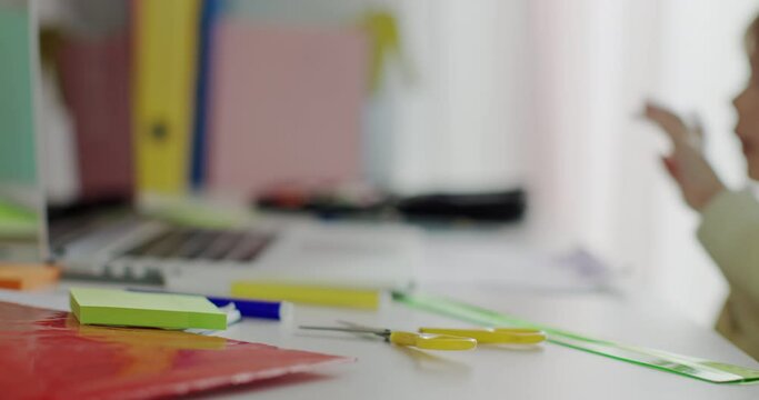 A young boy is attentively engaged in e-learning at his desk, surrounded by colorful stationery, using a laptop.