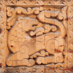 Wooden relief carving of a lion, displaying intricate traditional craftsmanship during the daytime.