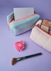 Cosmetic pencil case with various cosmetics and a makeup brush and flower