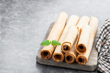 Delicious of waffer rolls with boiled condensed milk on gray background