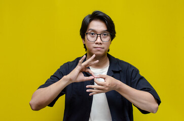 asian young students happily using sign language isolated against yellow background. asian man...