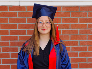 The image shows a young adult wearing a blue graduation cap and gown, indicating recent graduation...
