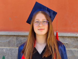 The image shows a young adult wearing a blue graduation cap and gown, indicating recent graduation...