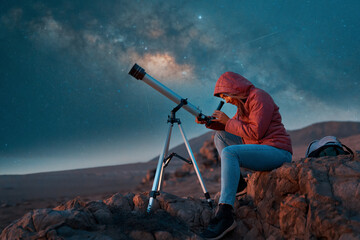 woman looking through the telescope observing the night sky in the desert  © freechoice