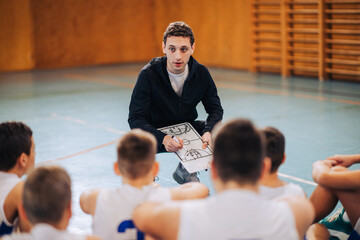 A basketball coach working on game plan with junior team on training.