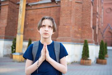 An 11 year old boy prays in front of a Catholic church