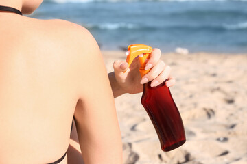 Young woman applying sunscreen cream on body at resort