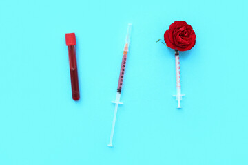 Medical syringes and test tube with blood on blue background