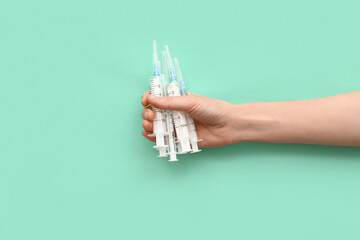 Female hand holding empty syringes on turquoise background