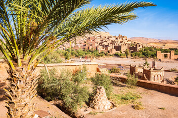 View of Ksar Ait Ben Haddou, old Berber adobe-brick village or kasbah in green oasis with palm...