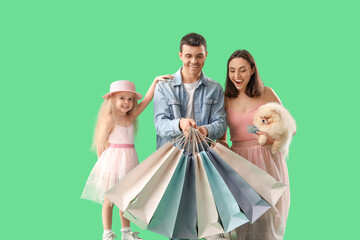 Happy family with dog and shopping bags on green background