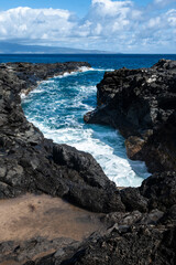 Rocky seascape and blue Pacific Ocean, waves crashing on lava rock, as a nature background
