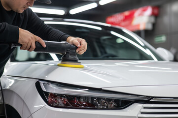 Process of polishing white car hood surface using orbital polishing machine. 
