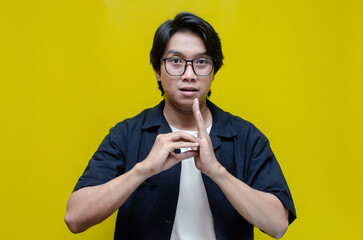 asian young students happily using sign language isolated against yellow background. asian man...