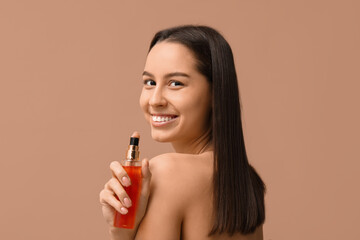 Young woman with cosmetics for hair treatment on beige background