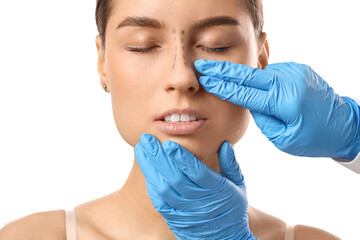 Surgeon hands touching woman nose before plastic surgery on white background, closeup