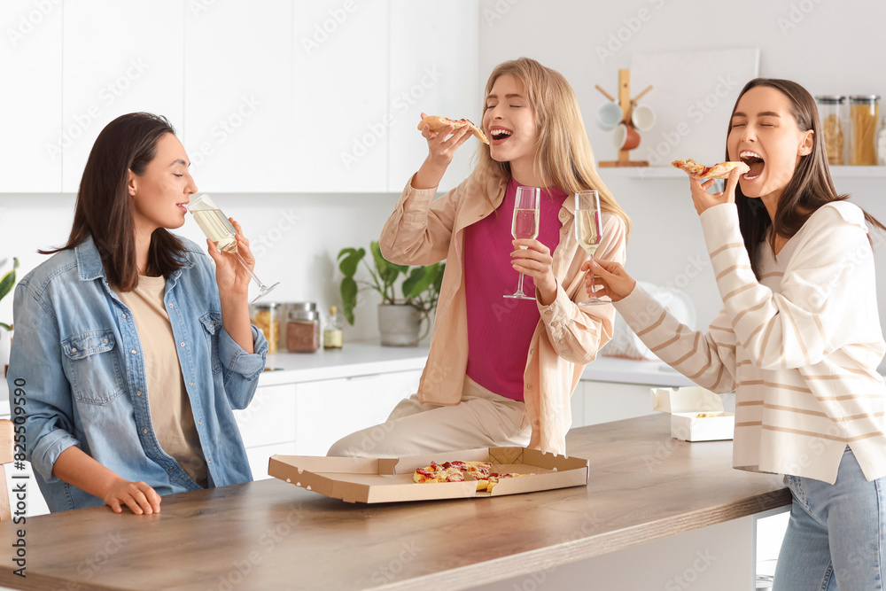 Poster Young women with champagne eating pizza at Hen Party in kitchen