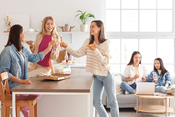 Fototapeta premium Young women with pizza drinking champagne at Hen Party in kitchen