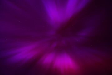 A stunning display of the aurora borealis with vibrant purple and pink hues over Riga and Jurmala, Latvia. Faint stars add to the ethereal beauty.