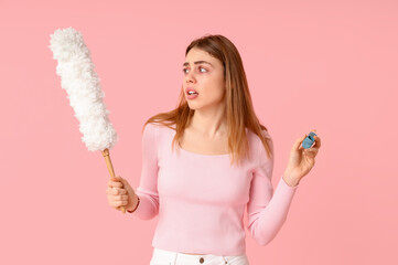 Young woman with pp-duster and inhaler suffering from allergy on pink background