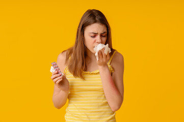 Young woman with skin allergy, pills and tissue on yellow background