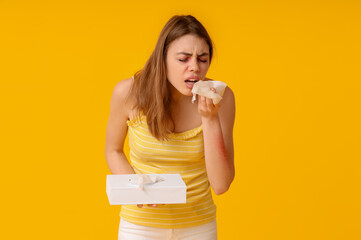 Young woman with skin allergy and tissue box on yellow background
