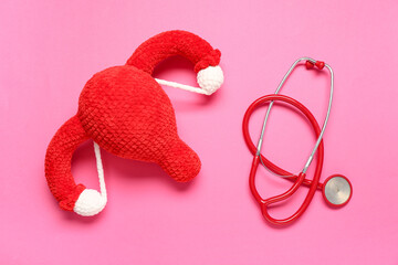 Knitted uterus and stethoscope on pink background